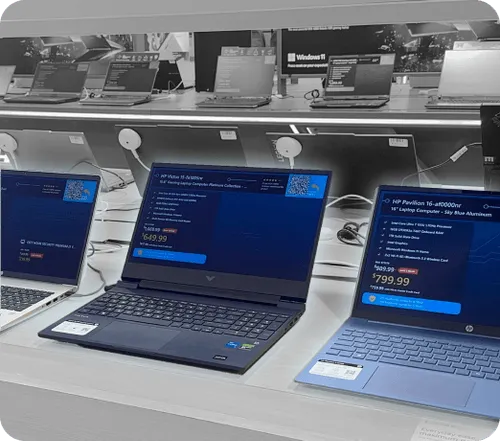 Retail display of multiple laptops showing pricing and specs, including HP Victus 16 and HP Pavilion 16 models.