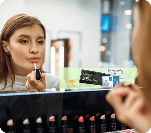 Woman applying lip gloss in front of a smart mirror displaying a 25% off coupon and product advertisements.